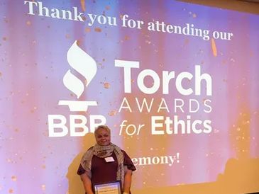 Person holding an award at the BBB Torch Awards for Ethics event.