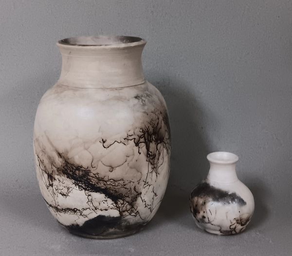 Two ceramic vases with black marbled patterns on a gray surface.