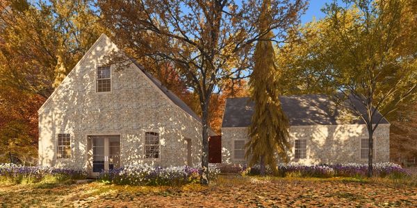 Custom stone house surrounded by autumn trees with fallen leaves.