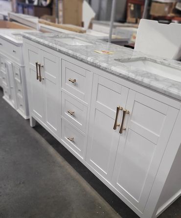 White bathroom vanity with marble countertop and brass handles.