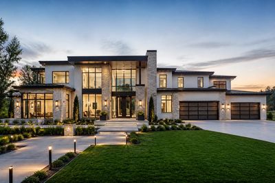 Modern luxury house at sunset with large windows and well-lit exterior.