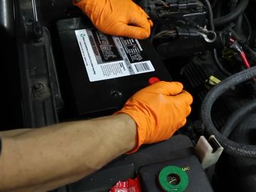 Car Battery Service tech installing a car battery at customers home