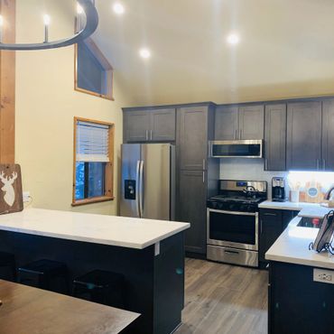 Modern kitchen with dark cabinets, stainless steel appliances, and white countertops.