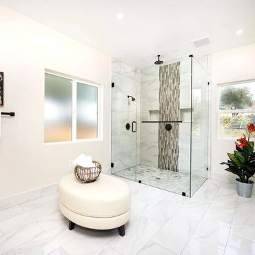 Modern bathroom with glass shower, white tiles, and decorative plants.