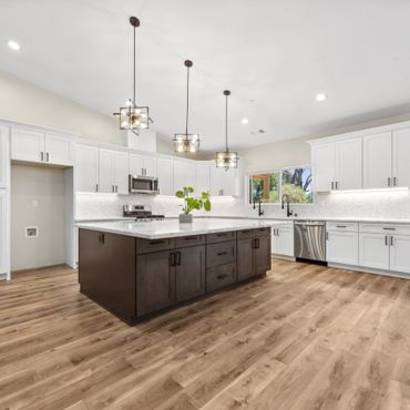 Modern kitchen with white cabinetry, large island, and pendant lighting.
