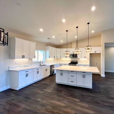 Spacious modern kitchen with white cabinets and dark wood flooring.
