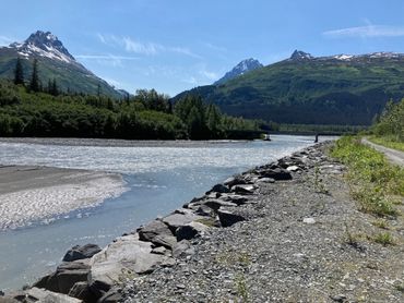 Scenic river with mountains and clear blue sky in the background.