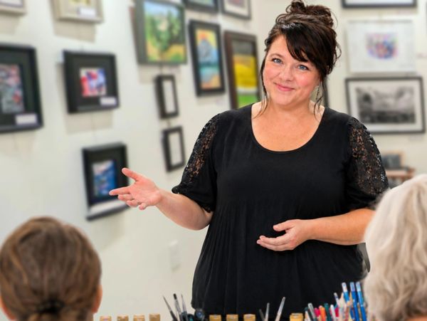Woman presenting art in a gallery or classroom.