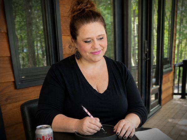 Woman sitting at a table, writing with a pen.