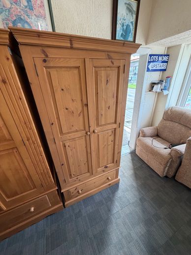 Wooden wardrobe with two doors and a drawer in a showroom.