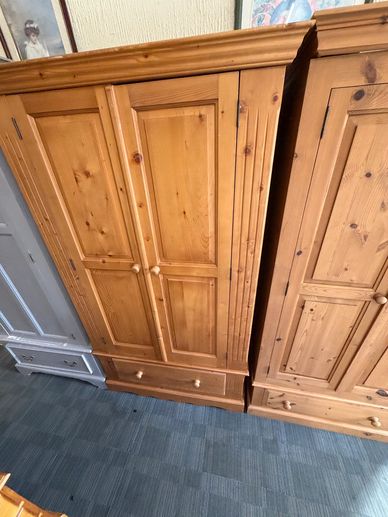 Wooden wardrobes with paneled doors and drawer bottoms on blue carpet.