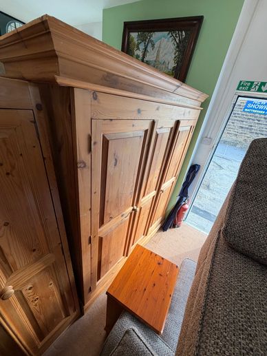 Large wooden wardrobe with paneled doors in a cozy room corner.
