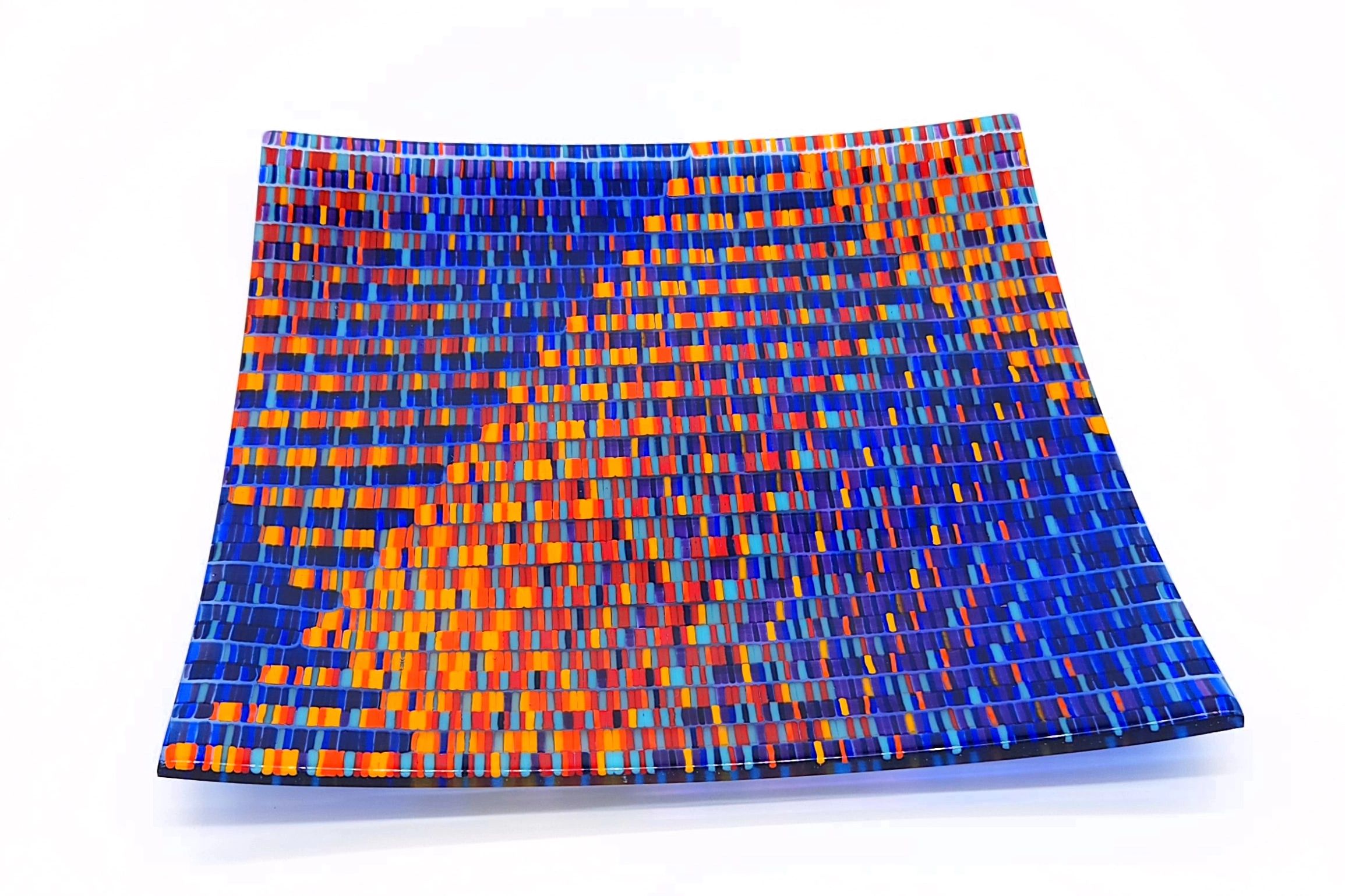 Square tapestry glass piece in colors of blue, red, and orange. 