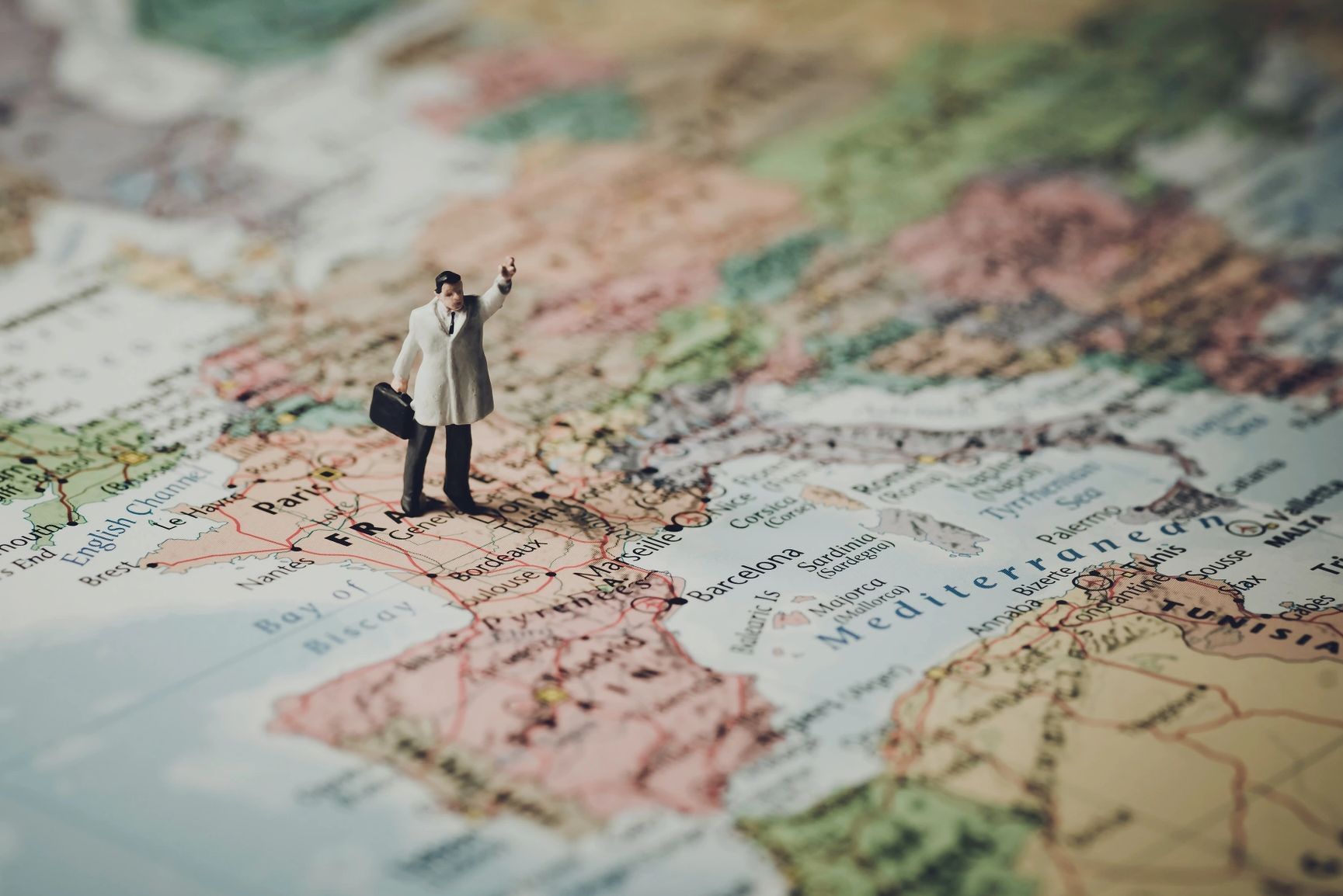 Small figure standing on map of Europe.