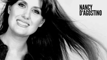 Black and white portrait of Nancy D'Agostino smiling with flowing hair.