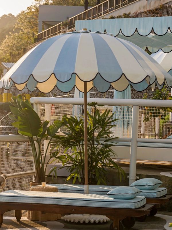 Blue and white striped umbrella over lounge beds.