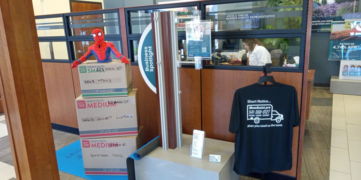Spiderman toy on top of labeled moving boxes in an office setting.