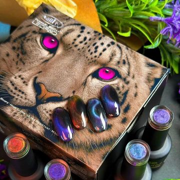 Vibrant nail polishes and art displayed on a leopard-themed box with striking pink eyes.