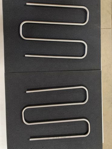 Two stainless steel U-shaped rods placed on black foam sheets.