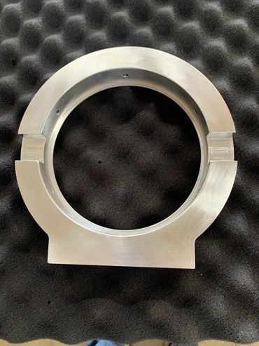 A metallic circular ring with notches on black textured foam.