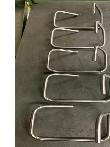 Five bent metal hooks arranged on a flat surface.