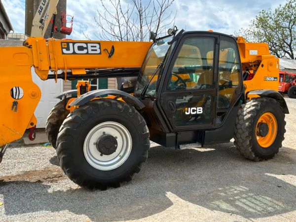 Yellow JCB telescopic handler parked outdoors on gravel.