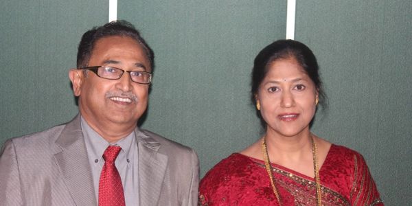 Man and woman posing for a photo, both dressed formally.