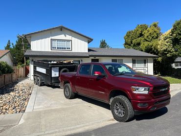 Truck and trailer parked on job site driveway. Trailer is full of debris.