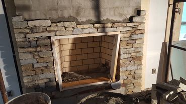 Thin ledge stone applied around firebox opening and fireplace legs