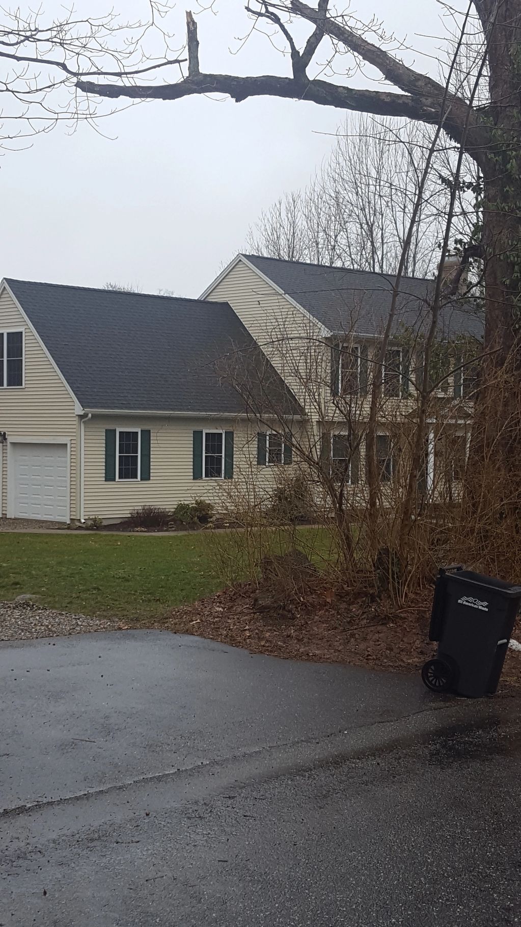 A beige house with green shutters on a cloudy day.