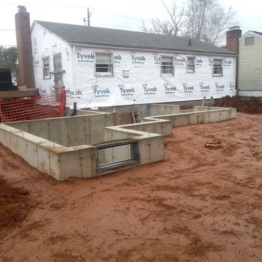 Concrete foundation installed and backfilled. The existing house siding has been removed