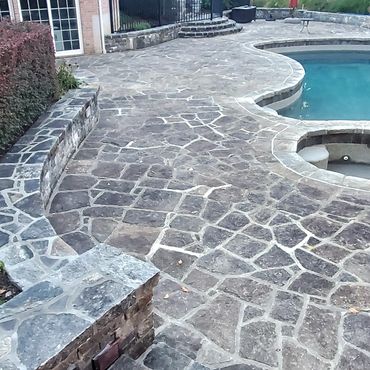Large pool granite stone patio with stairs to upper level