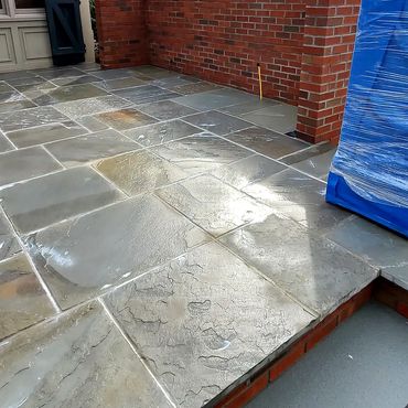 A heavy coat of siloxane sealer is applied to the bluestone and the brick privacy wall