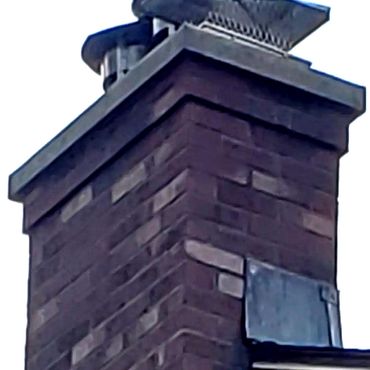 The chimney is complete and the steel rain caps are installed. The concrete cap extends out over the