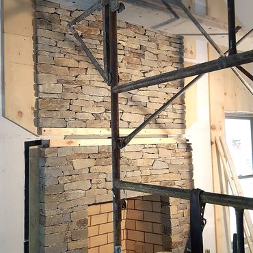 Thin real stone to the ceiling, this is a dry stack method with no mortar joints showing