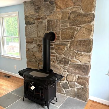 Brand new wood stove sitting on the beautiful bluestone hearth backed up by New England Fieldstone v