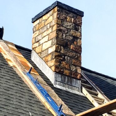 Stone veneer chimney with lead through flashing