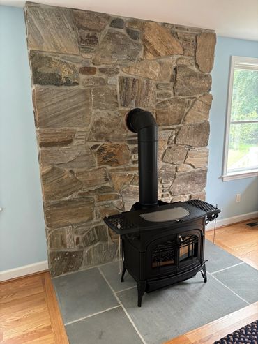 Wood stove installed on the beautiful bluestone hearth with New England Fieldstone veneer behind it