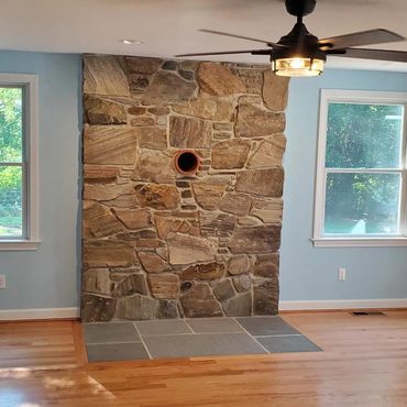 Stone veneer and hearth for a new wood stove with hardwood flooring and beautiful pastel walls