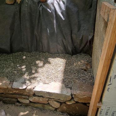 The new stone wall base is set and compacted with filter fabric and pea stone installed behind the s