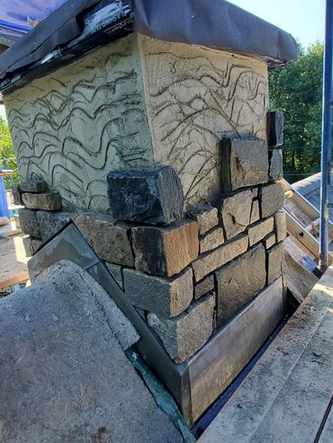 New stone veneer is mortared to the plastered structure
