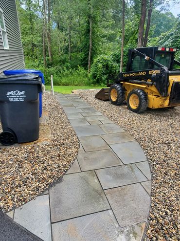 Natural granite slabs installed for the garbage barrels, bluestone walkway and 3/4" crushed stone fo