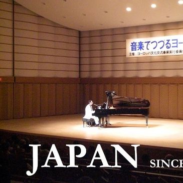 mario moita no festival de sakai, japao, tocando um piano de cauda, num palco grande.