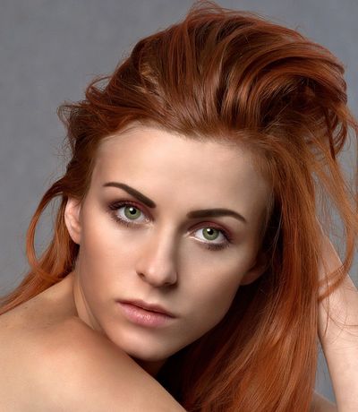 A woman with red hair, green eyes and defined eyebrows.