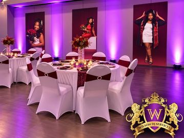 Elegant party setup with white chairs and purple lighting.