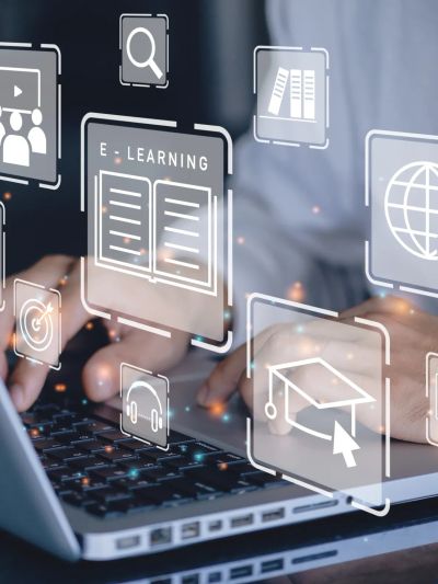 Hands typing on laptop with floating e-learning icons.