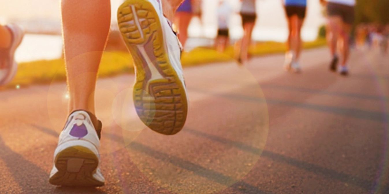 Close-up of runners' shoes on a sunlit path during a race or jog.
