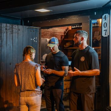 Three people chatting outside a wooden door at night.