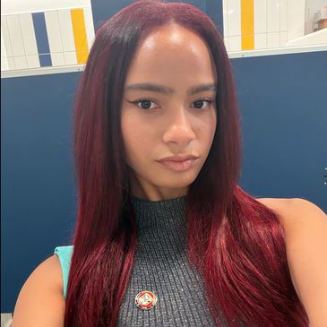 A woman with long straight burgundy hair and winged eyeliner.