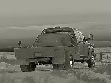 Heavy-duty pickup truck with a flatbed on a snowy rural road.